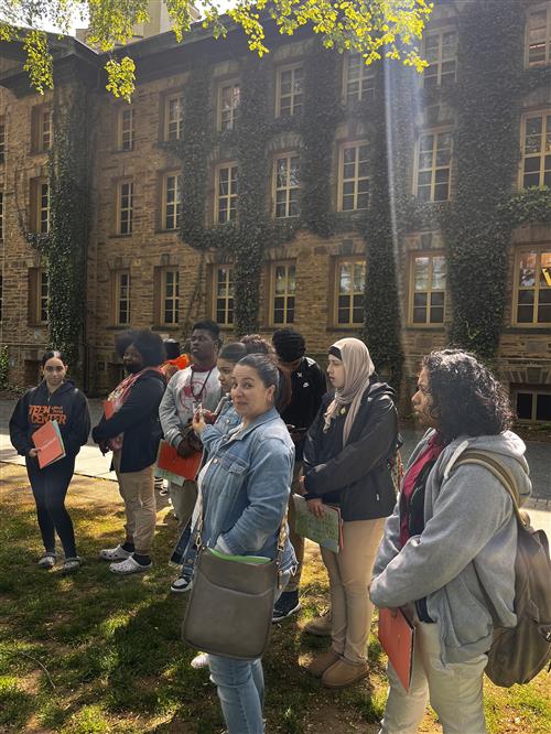 people standing in front of an ivy covered building.